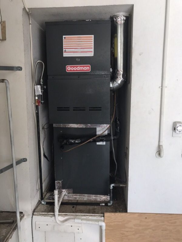 5 ton Goodman brand furnace being installed into a space in the wall in ceres.